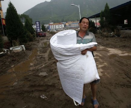2012年7月25日、河北涞水県苟各庄村で、村民の徐煥文は洪水に押し流された家から布団を抱いてきて、急いで親友の家へ投宿します。